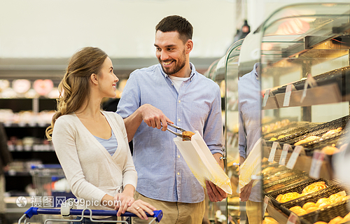 食物销售消费主义人的幸福的夫妇与购物车杂货店超市烘焙部门购买包馅饼